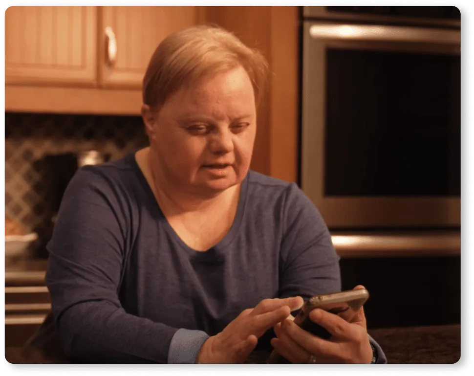 Woman with Down Syndrome looking at MagnusCards mobile app in her kitchen