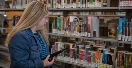 Woman using MagnusCards app to find a book at the library