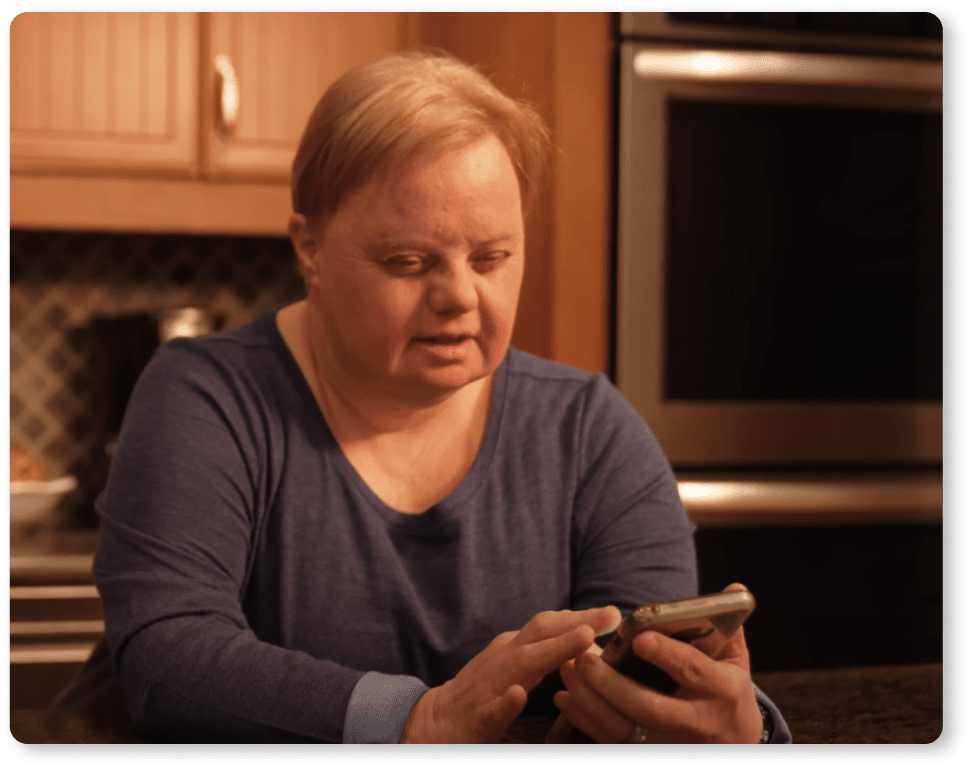 Woman with Down Syndrome looking at MagnusCards mobile app in her kitchen