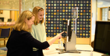 Woman shows teen how to check in at Oishei children's hospital