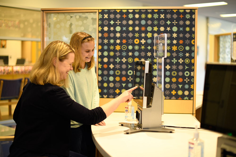 Woman shows teen how to check in at Oishei children's hospital