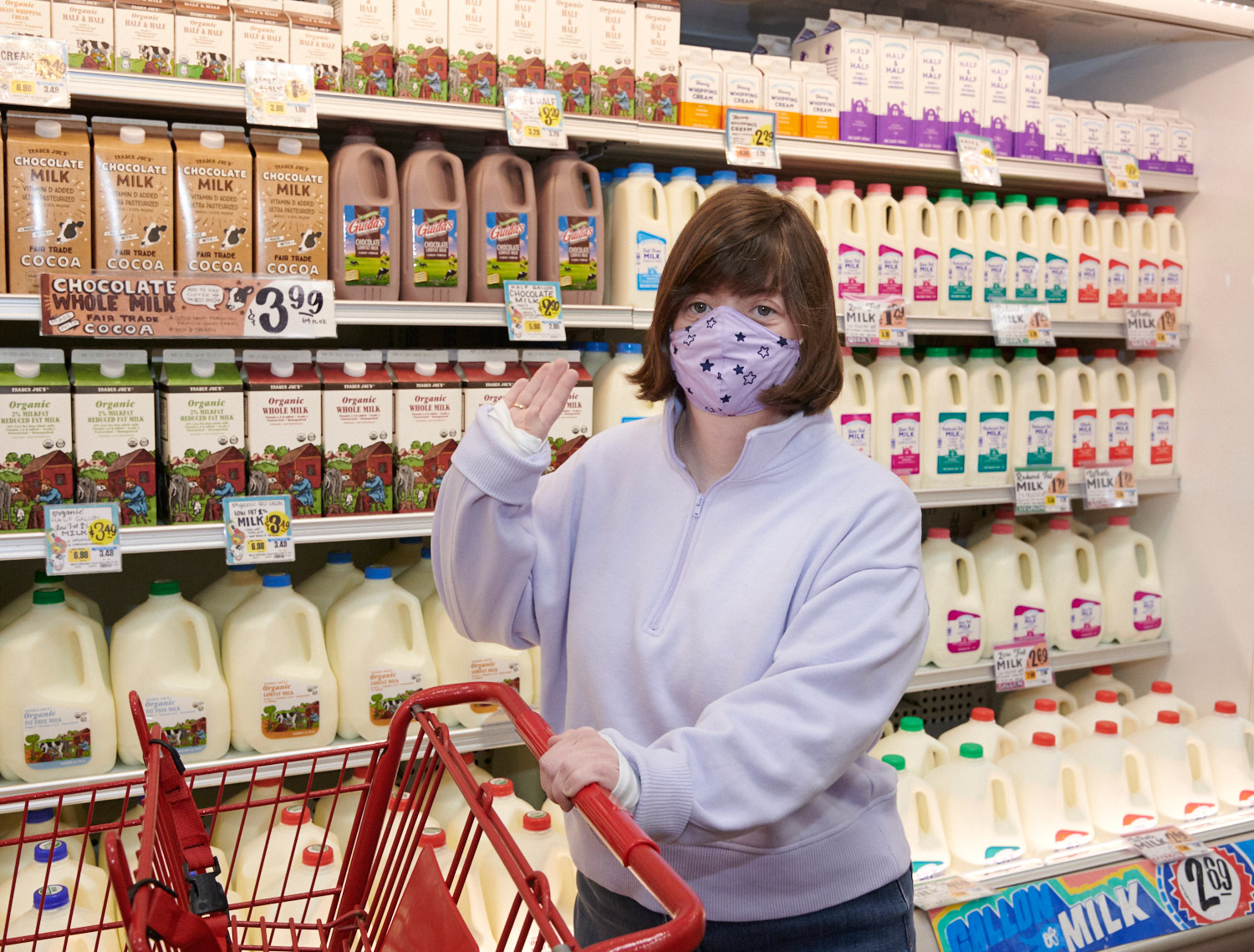 Young woman wearing mask waving in grocery store (Trader Joe's).